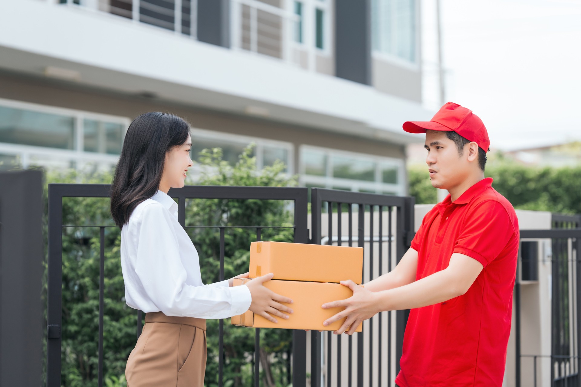 Asian people received product box from male delivery service person, modern e-commerce, home deliveries, convenient shopping experience, trustworthy doorstep service captured in moment.